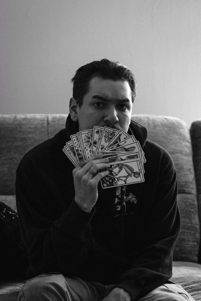 Christopher Parrish holding a fan of tarot cards, black and white portrait